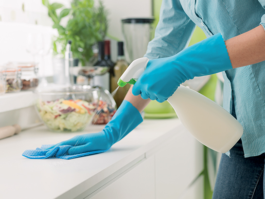 photo d'une aide-ménagère qui nettoie un plan de travail dans une cuisine