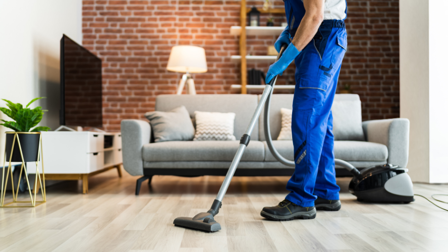 photo d'un aide-ménager qui passe l'aspirateur dans un salon