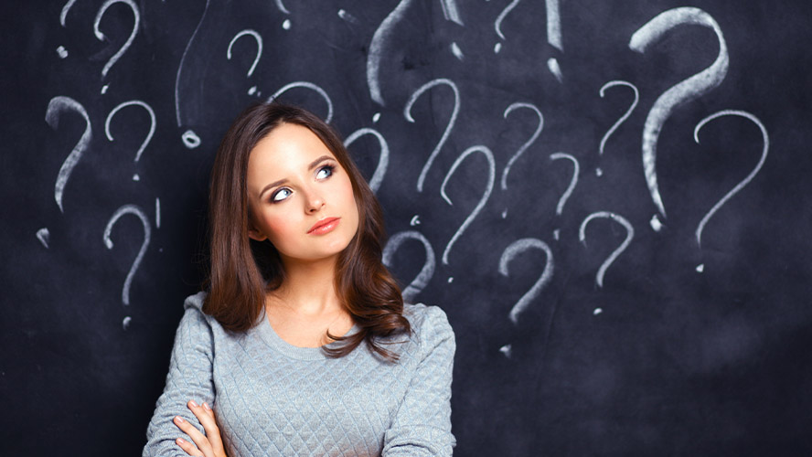 Jeune femme devant un tableau avec points d'interrogation