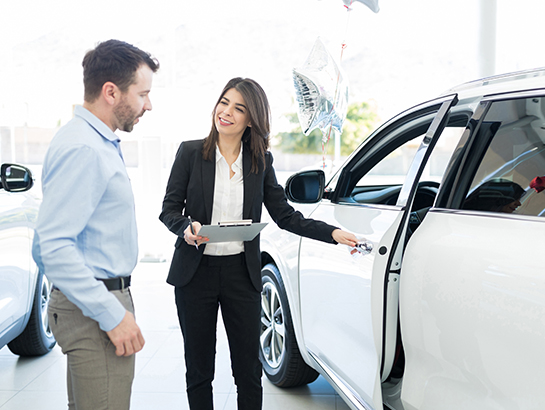 Vendeuse automobile qui présente un véhicule à son client