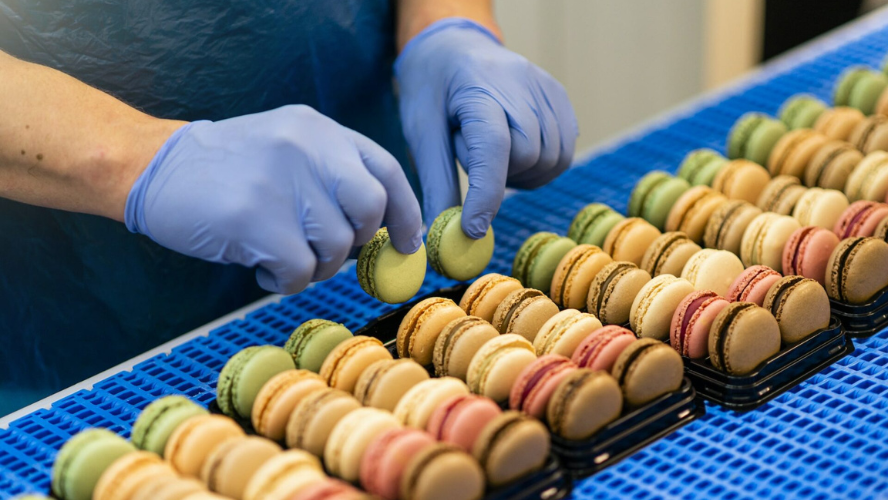 Photo des mains d'une personne qui trie et range des macarons 