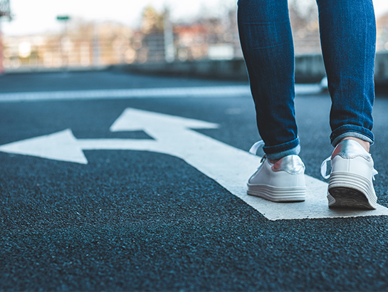 Une personne qui marche sur une flèche au sol