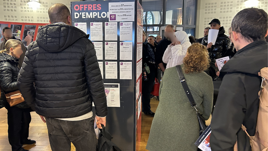 Photo d'illustration, des personnes dans un salon dont une consulte des offres d'emploi affichées